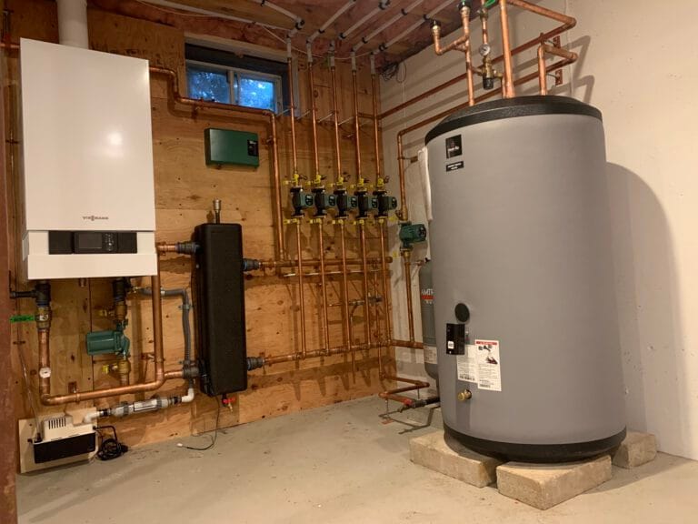 High-efficiency boiler system installation with copper piping and circulation pumps.