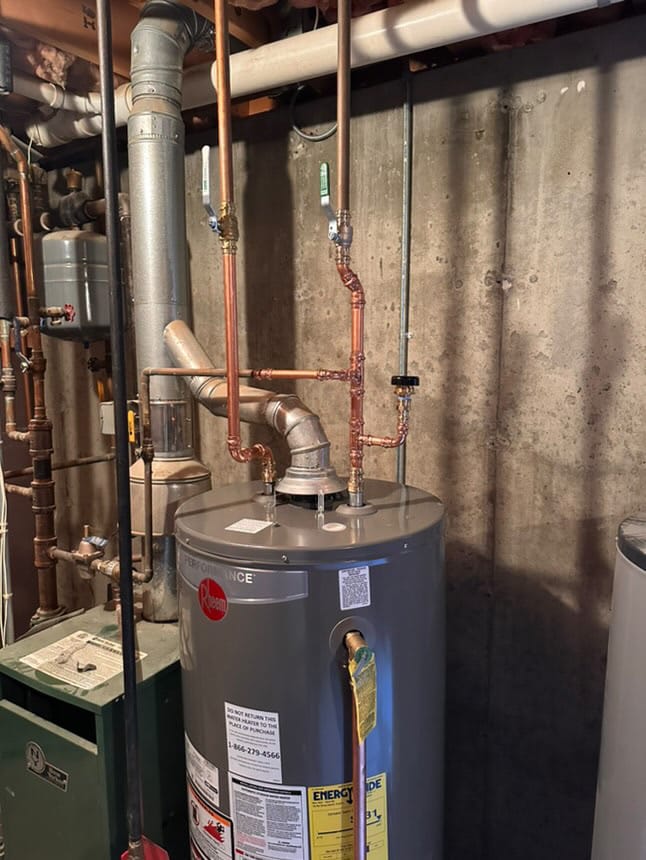 Water heater installation with copper piping and venting system in a basement.