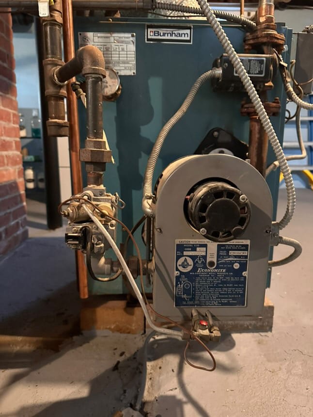 Burnham oil-fired boiler system with copper and black iron piping in a basement.