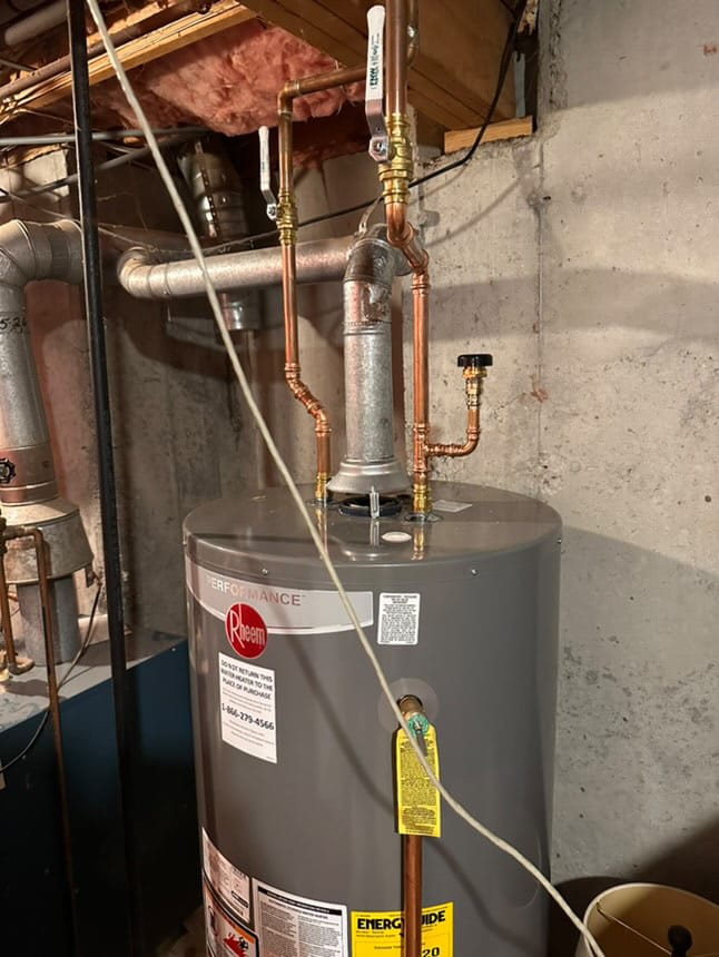 Water heater installation with copper piping and venting system in a basement.