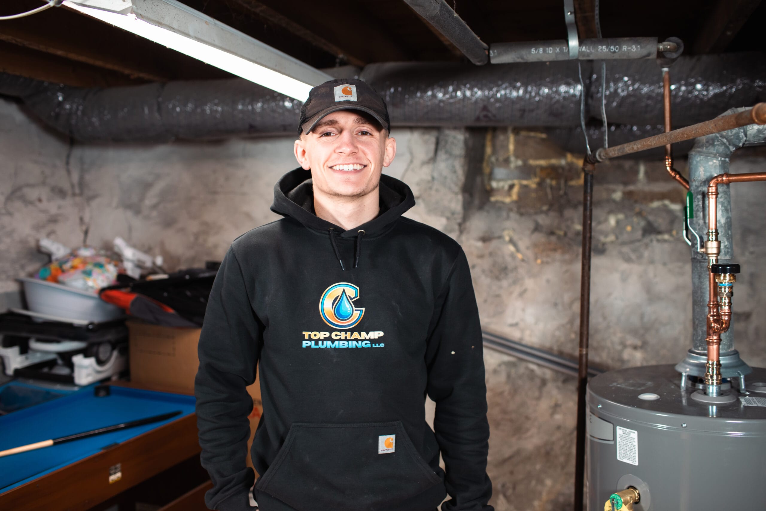 Michael White, owner of Top Champ Plumbing, standing next to a water heater, ready to provide expert plumbing services