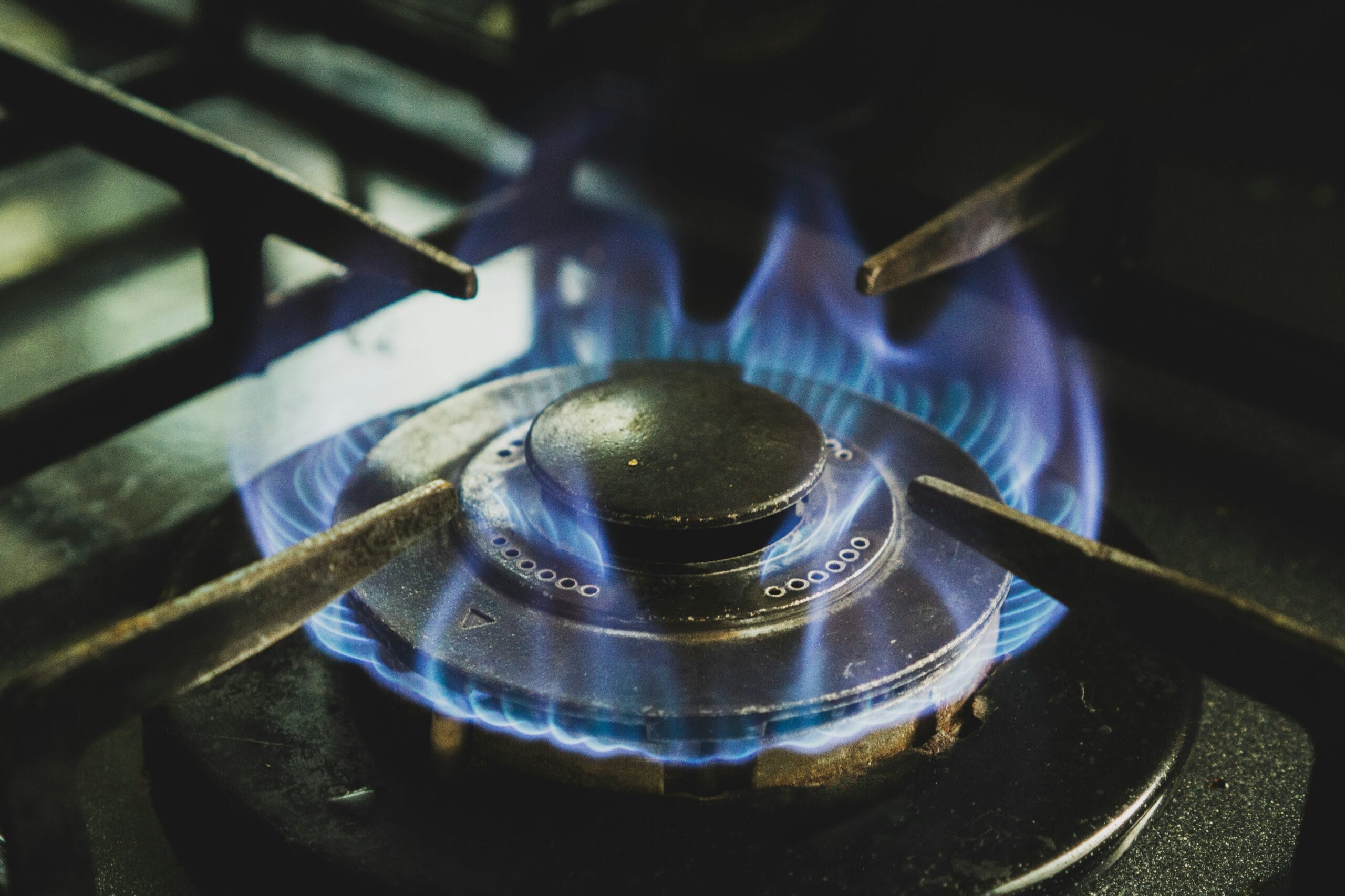 Close-up of a gas stove burner with blue flames, highlighting safe and efficient natural gas usage in residential kitchens.