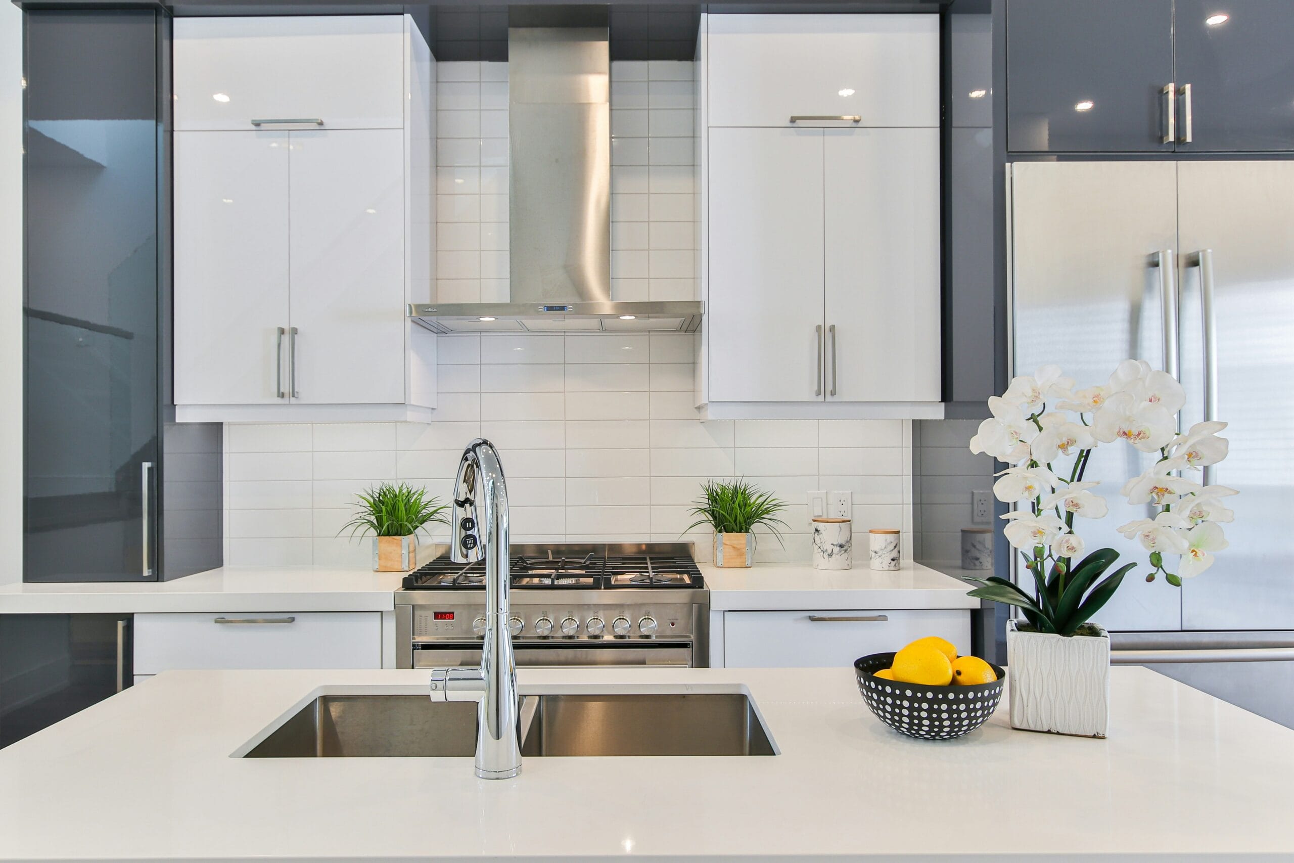 Modern kitchen with a stainless steel double sink, high-arc faucet, and white cabinetry, featuring a gas stove.